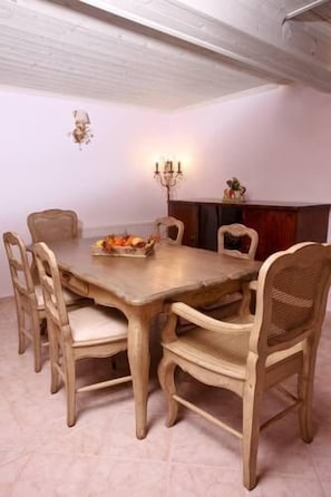 A dining area with a wooden table and chairs, a candelabra, and a small decorative item on the mantel. - Aegean Diamonds Boutique Villas (Skopelos)