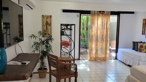 Una sala de estar con sofá, una mesa de comedor con sillas, televisor y una planta en maceta.