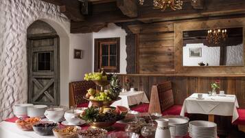 A dining area with a buffet setup, wooden walls, and a chandelier.