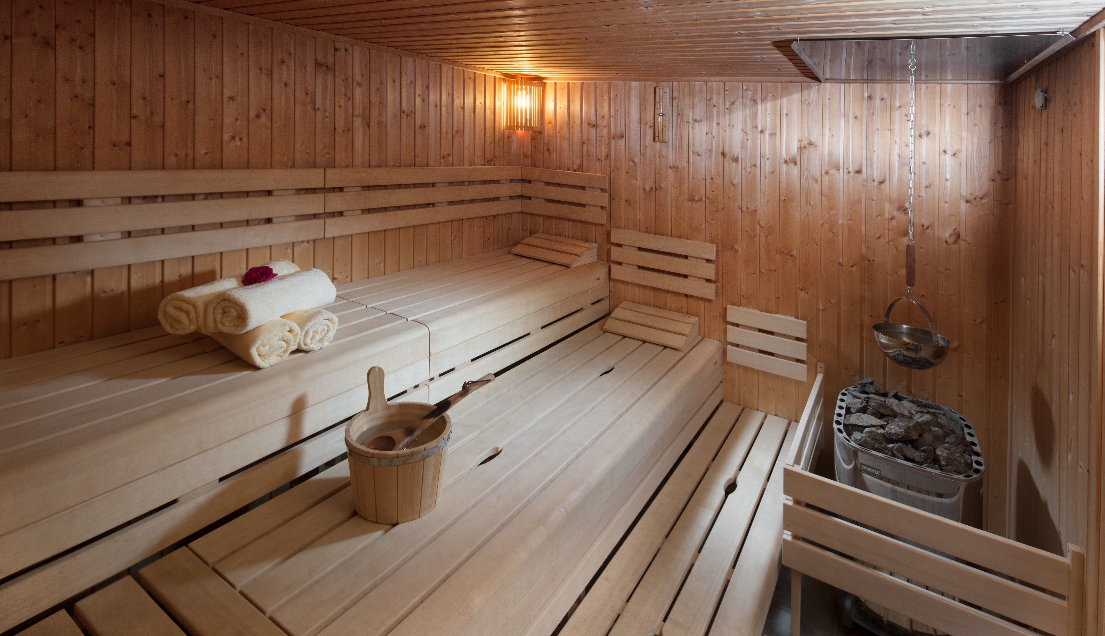 Un sauna avec des bancs en bois, un seau et des serviettes.