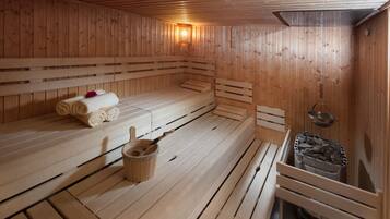 Un sauna avec des bancs en bois, un seau et des serviettes.