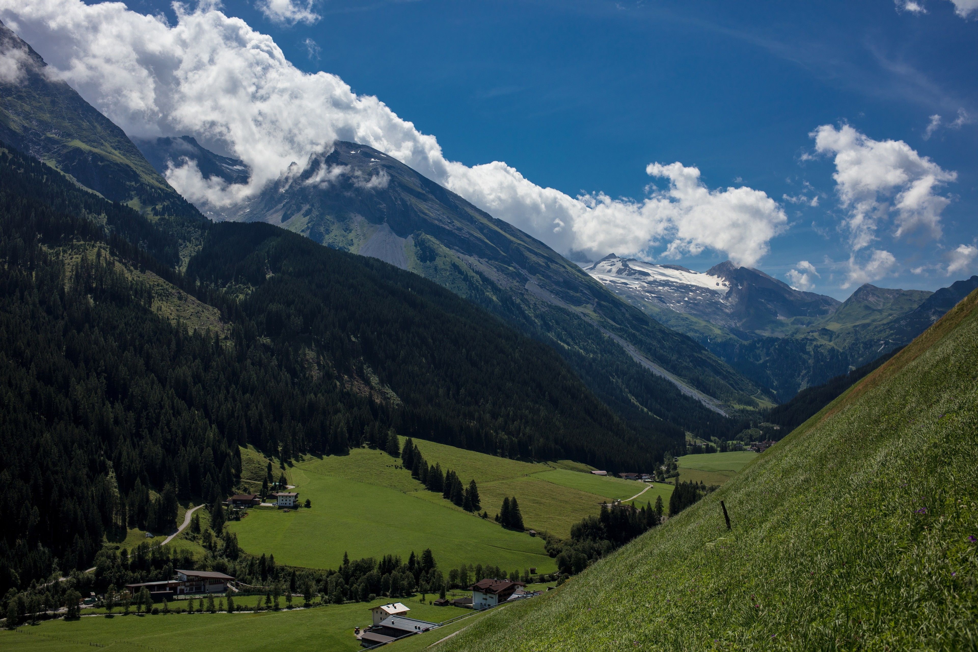 Eine Berglandschaft mit einem Tal, Häusern und blauem Himmel.
