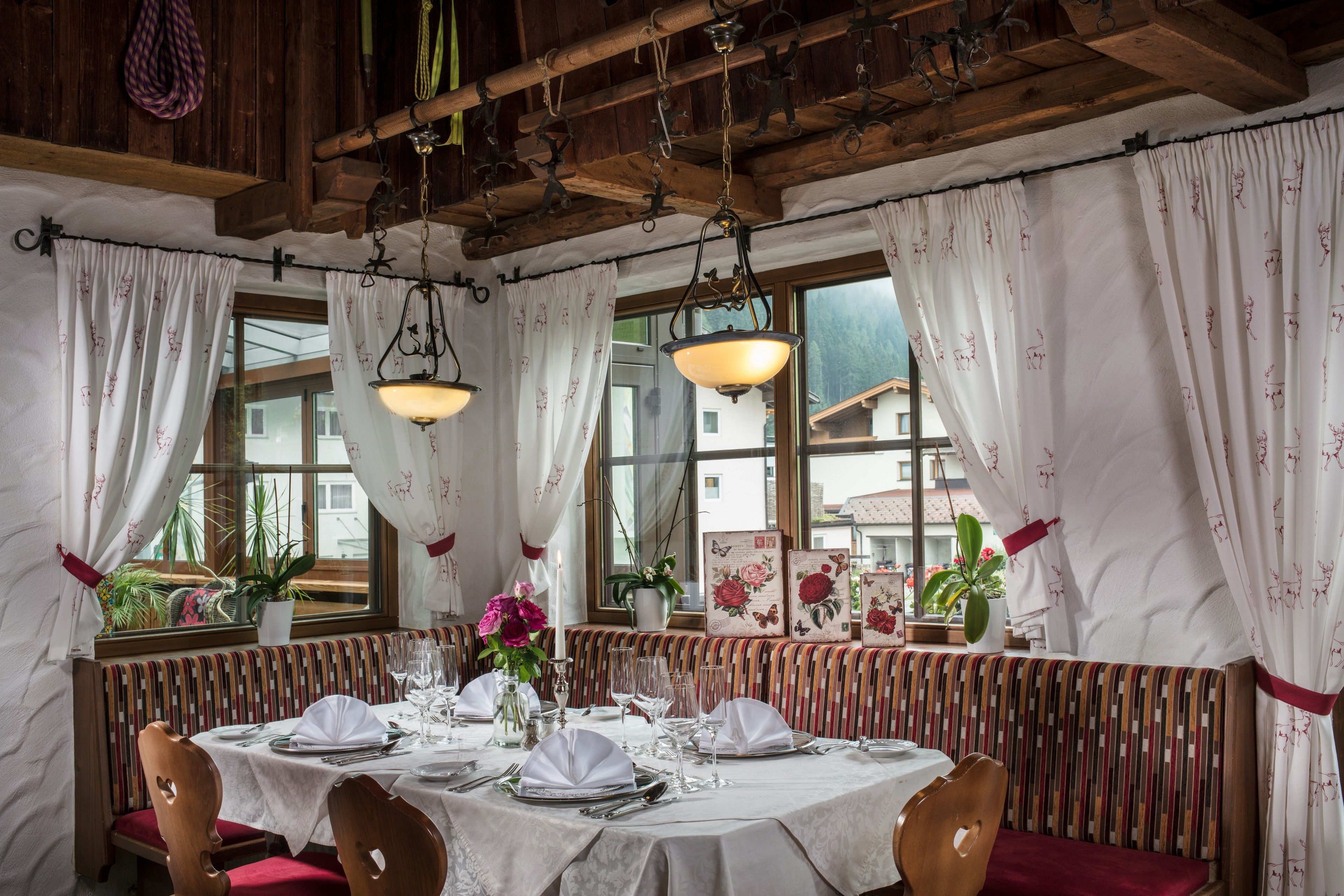 A dining area with a round table set for four, wooden chairs, and a bench with a striped cushion.
