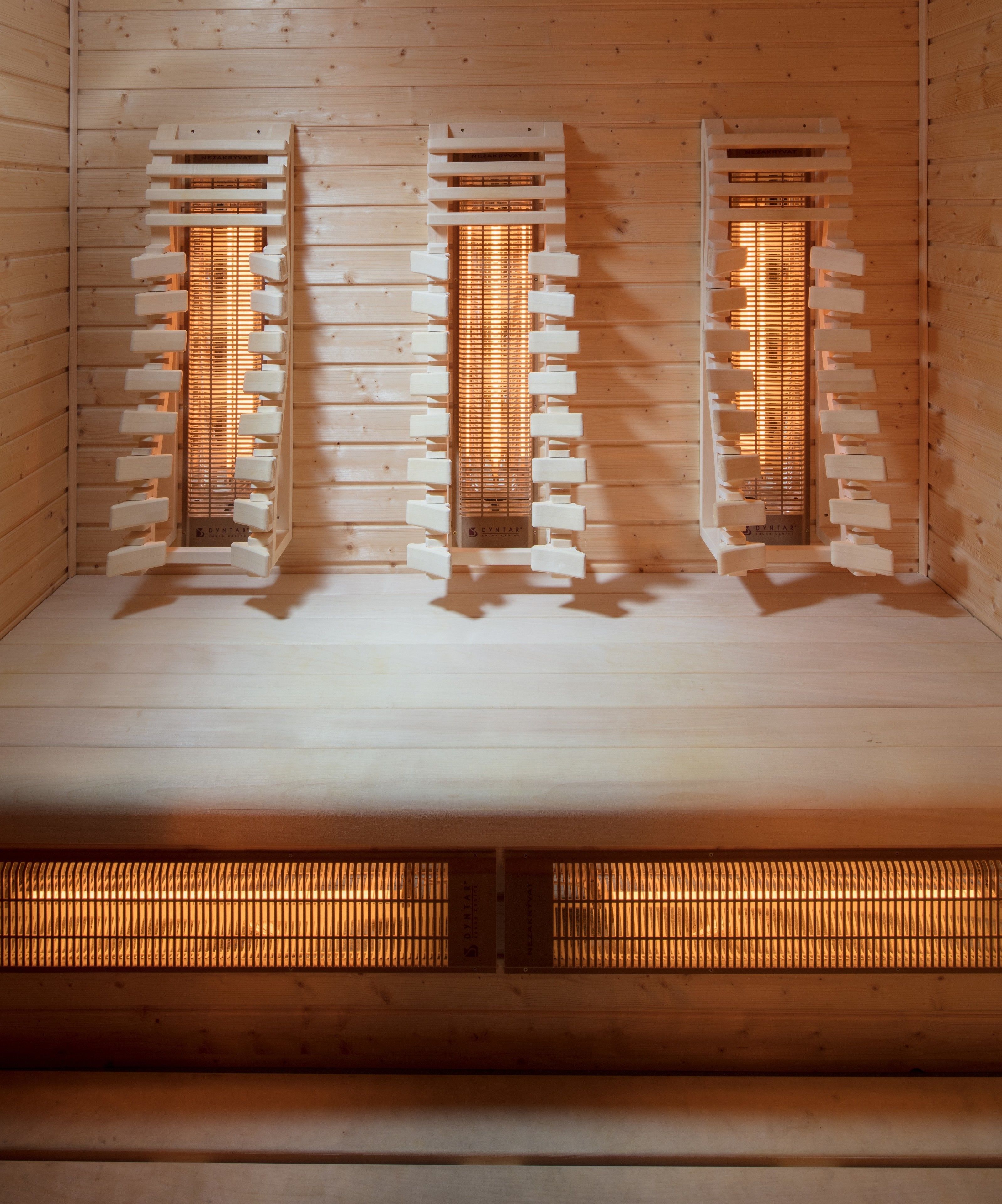 Una sauna con tres bancos de madera y un elemento calefactor central.