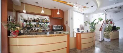 Zona de bar con una barra curva, lámparas colgantes y una variedad de botellas.