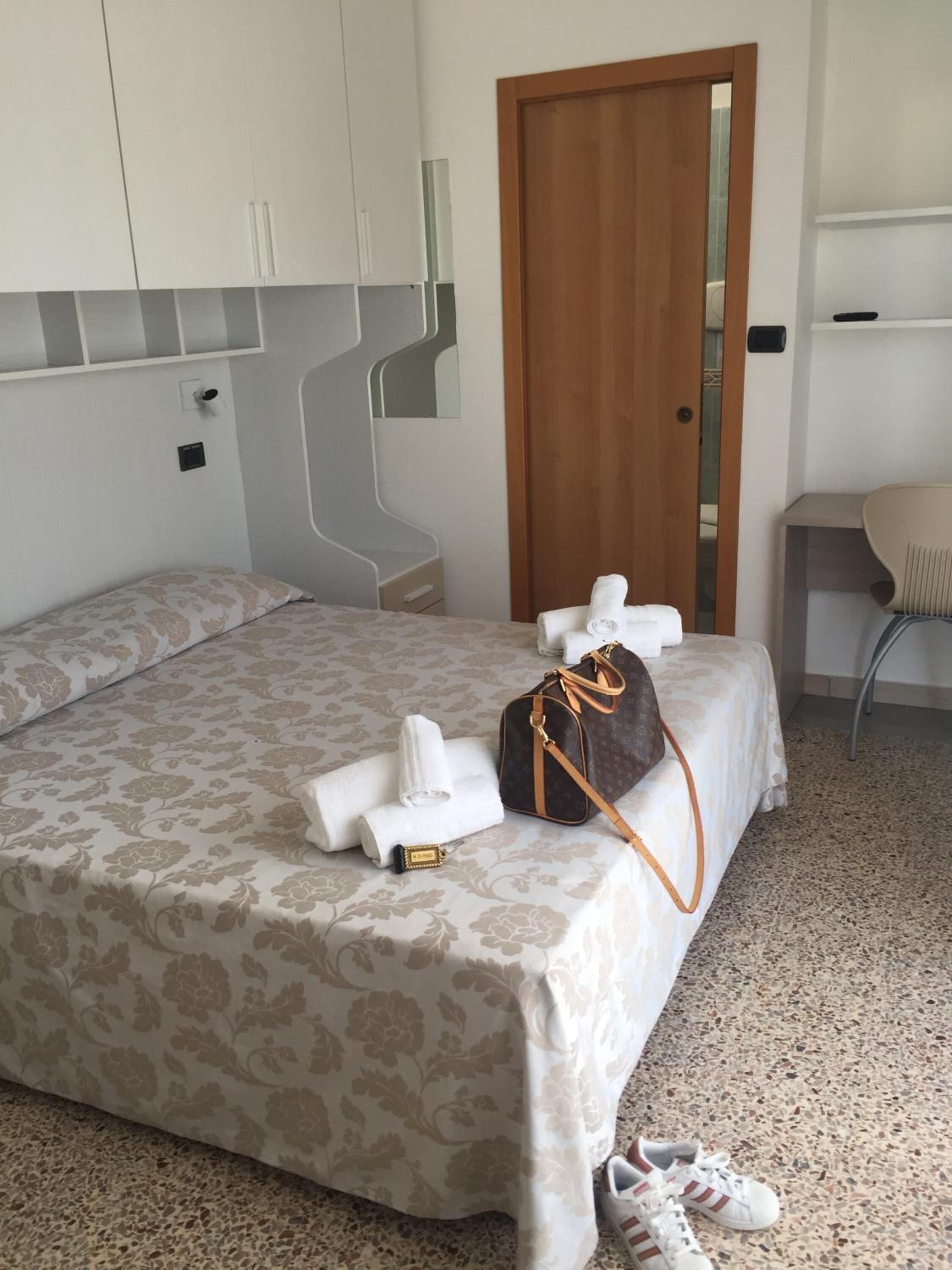 Una habitación de hotel con una cama, una puerta de madera, una silla y una mesita.