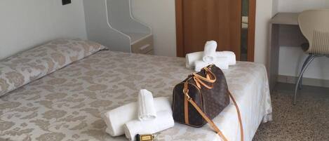 Una habitación de hotel con una cama, una puerta de madera, una silla y una mesita.