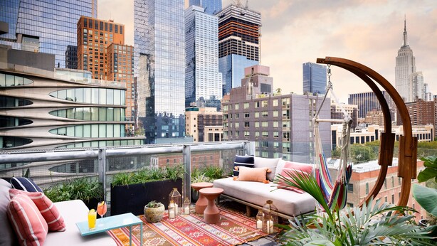 A rooftop terrace with a modern sofa, a small table with a drink, and a view of the city skyline. - Hotel Alameda Highline (New York)