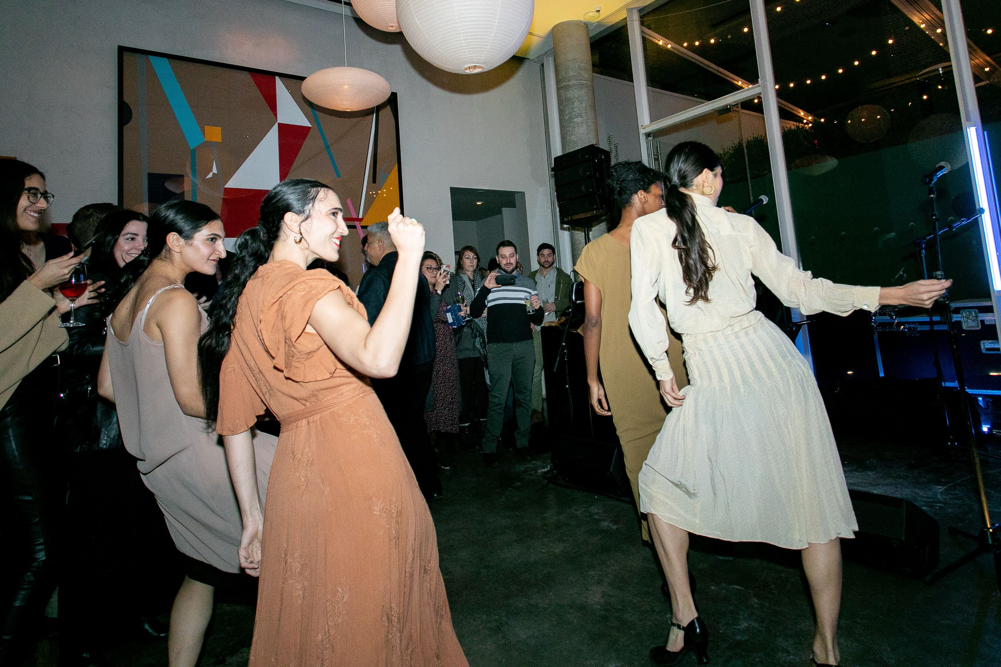 Un grupo de personas en un evento social en un espacio moderno con grandes ventanales y decoración contemporánea.