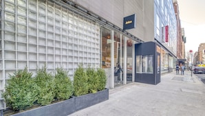 A modern building with a glass facade, a sign reading "Selina," and a black awning over the entrance. - Hotel Alameda Highline (New York)
