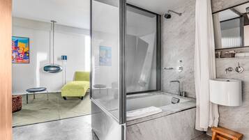 A modern bathroom with a glass-enclosed shower, a large bathtub, and a marble-tiled floor.