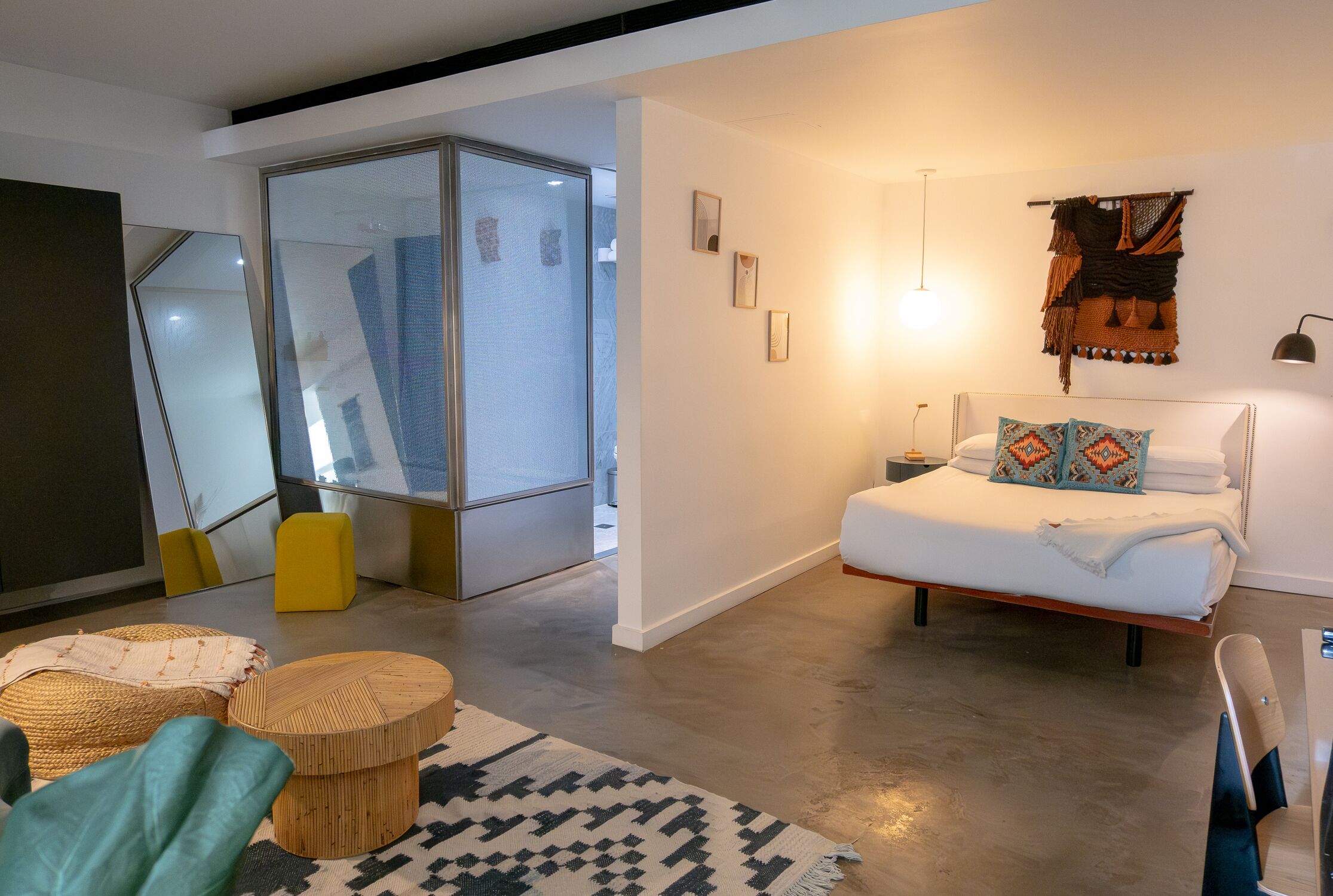 Een moderne slaapkamer met een bed, nachtkastje en een grote spiegel.