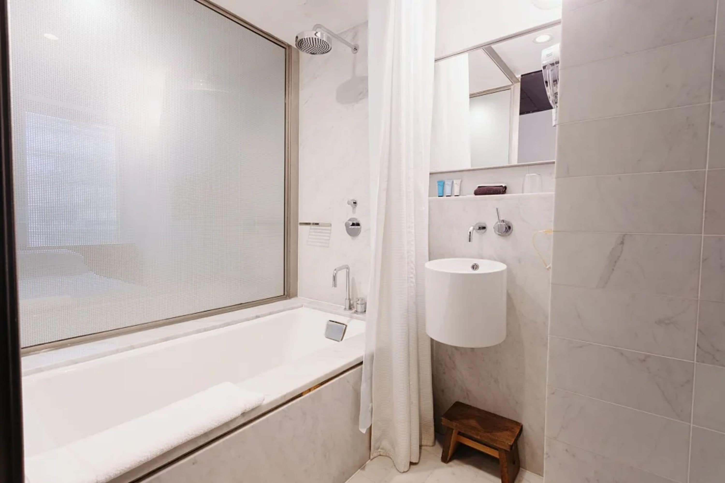 A modern bathroom with a bathtub, a shower, and a sink.