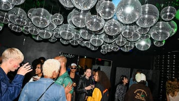 Une pièce dont le plafond est décoré de nombreuses boules à facettes, et où un groupe de personnes s’est rassemblé au centre.