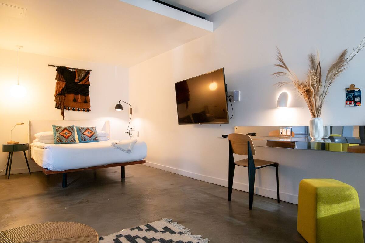 A modern bedroom with a bed, bedside table, lamp, and a mounted TV.