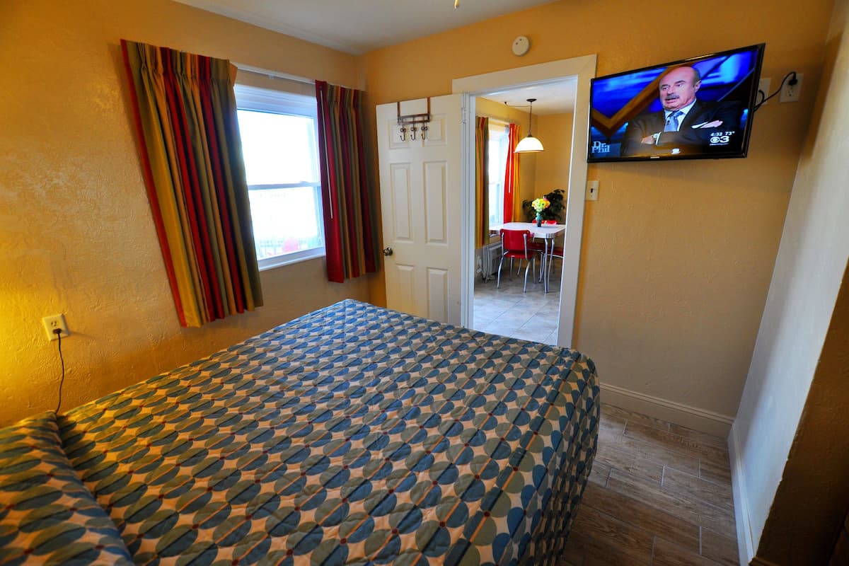 Une chambre d’hôtel avec un lit, un téléviseur fixé au mur et une porte donnant sur un coin repas.