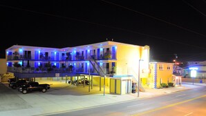 A multi-story motel with balconies, a parking area, and a visible vending machine. - Nantucket Inn & Suites (Wildwood)
