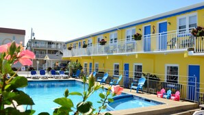 A hotel with a pool area, multiple balconies with blue doors, and outdoor seating. - Nantucket Inn & Suites (Wildwood)