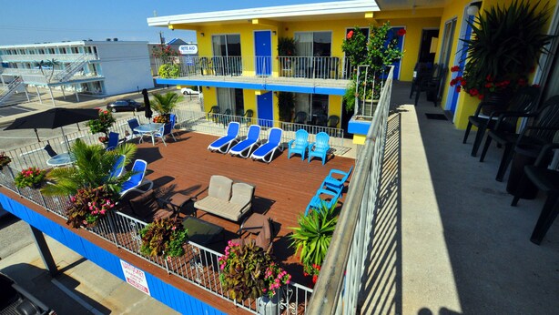 A hotel with a rooftop deck featuring sun loungers, chairs, and potted plants. - Nantucket Inn & Suites (Wildwood)