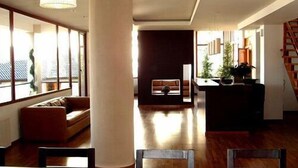 A spacious living area with a large window, a sofa, a coffee table, and a dark-toned entertainment unit. - View Hotel BRC (San Carlos de Bariloche)
