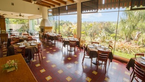 A restaurant with outdoor seating, large windows, and a view of greenery. - Hotel Posada Loma (Fortin de las Flores)