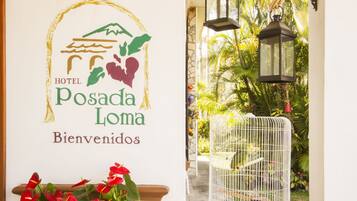 Señal de bienvenida para HOTEL Posada Loma con un logotipo que muestra una montaña, olas y un corazón.