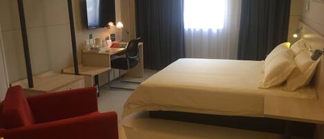 Une chambre d’hôtel comprenant un lit, un bureau, une chaise, une télévision et une armoire.