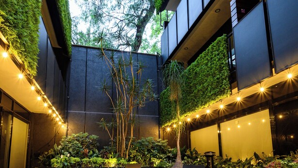An indoor courtyard with a seating area, greenery, and string lights.