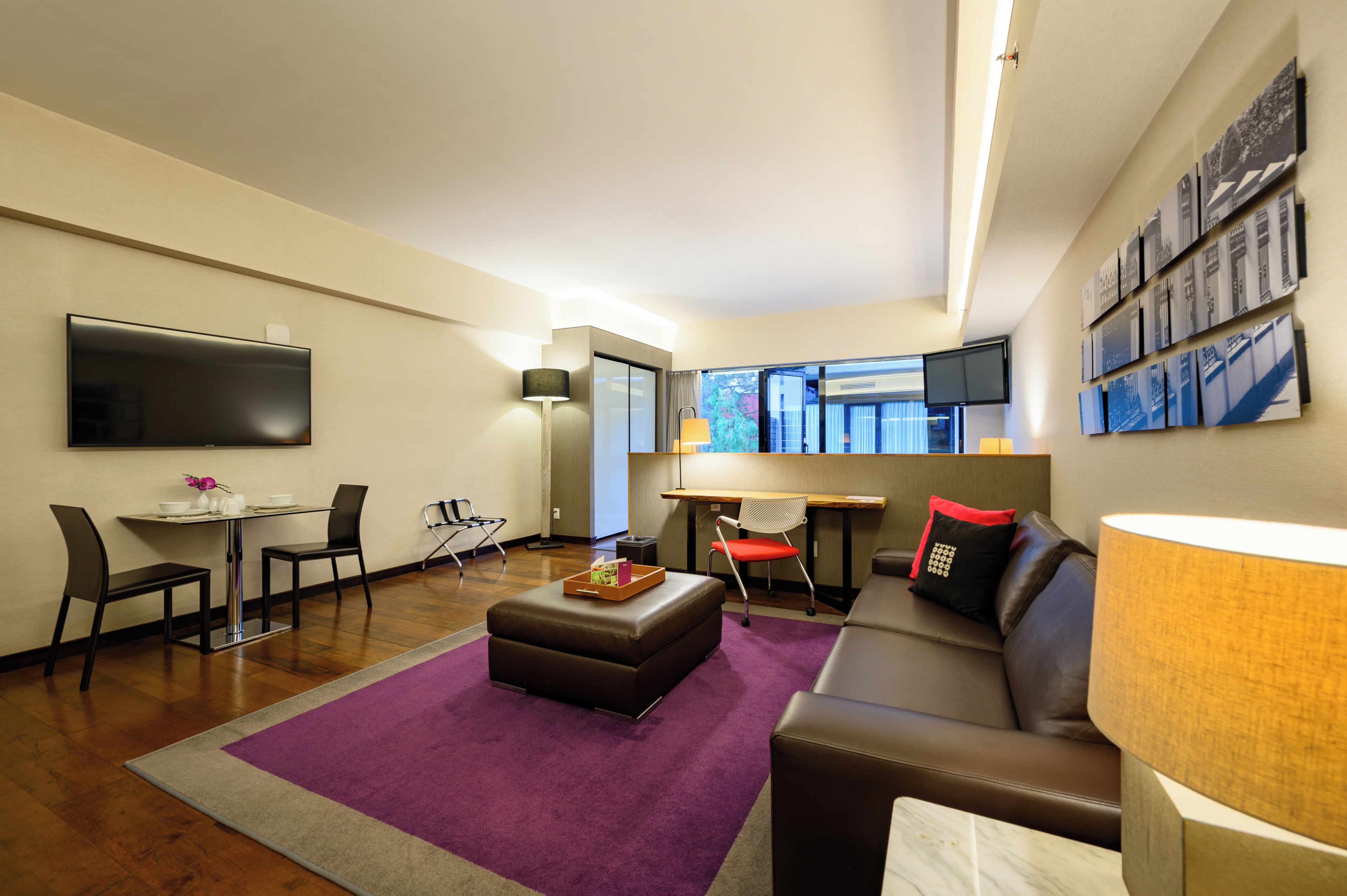 Un salon moderne comprenant un canapé, un pouf, une table basse et un coin repas avec des chaises et une table.