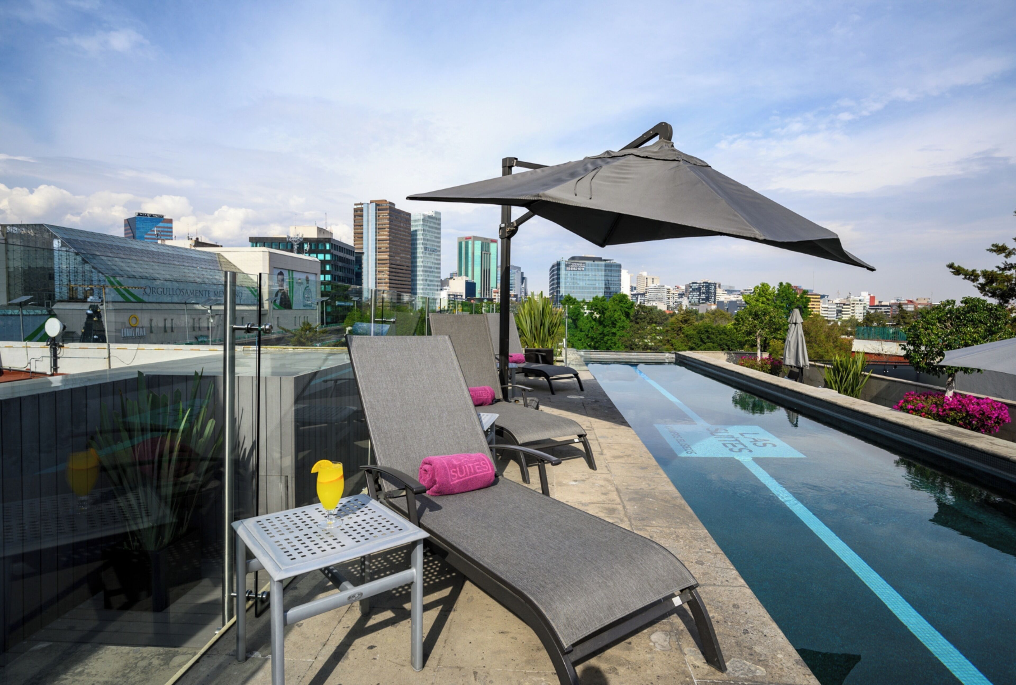 A rooftop pool area with lounge chairs, a table, and a large umbrella.