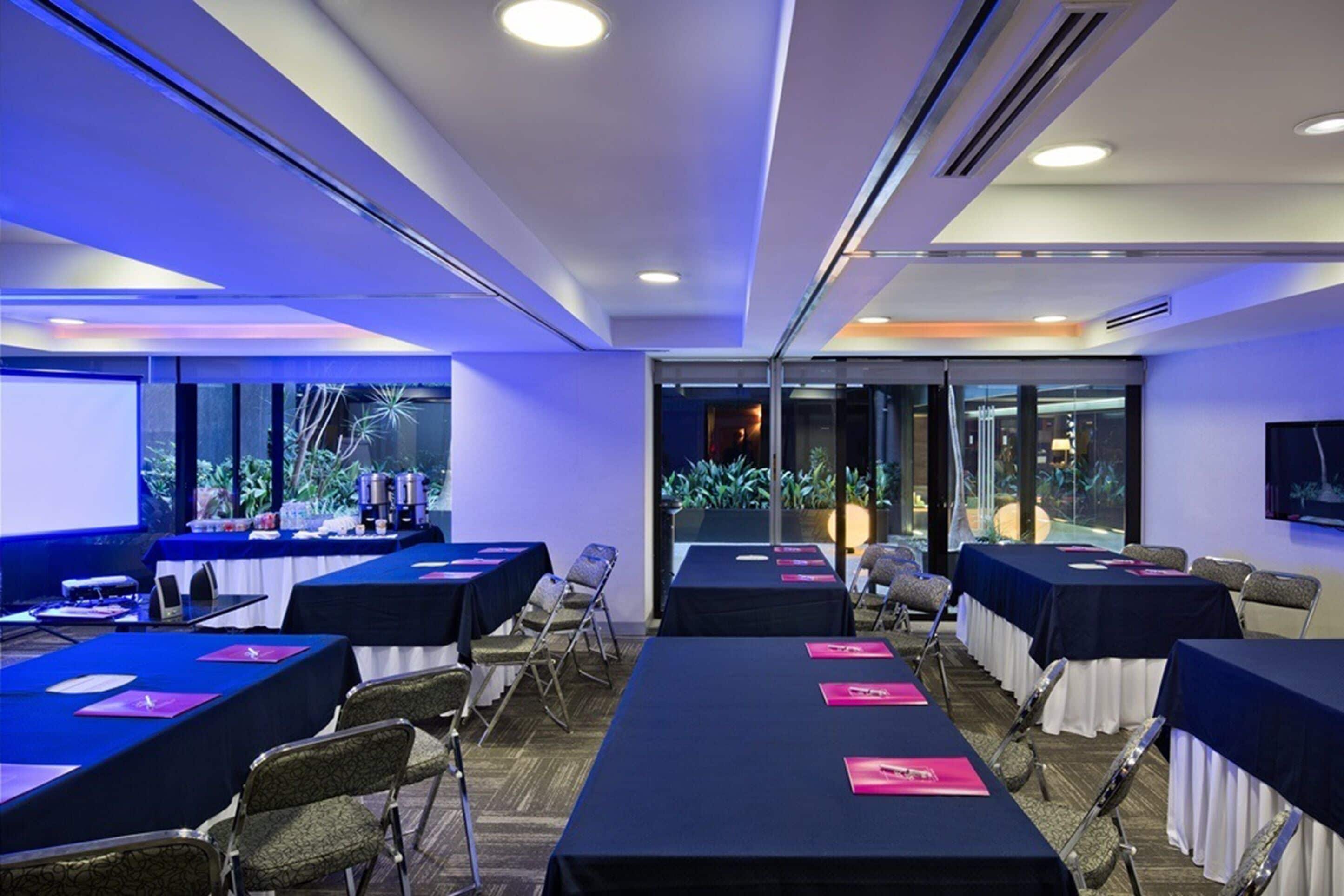 A conference room with tables, chairs, and a projector screen.