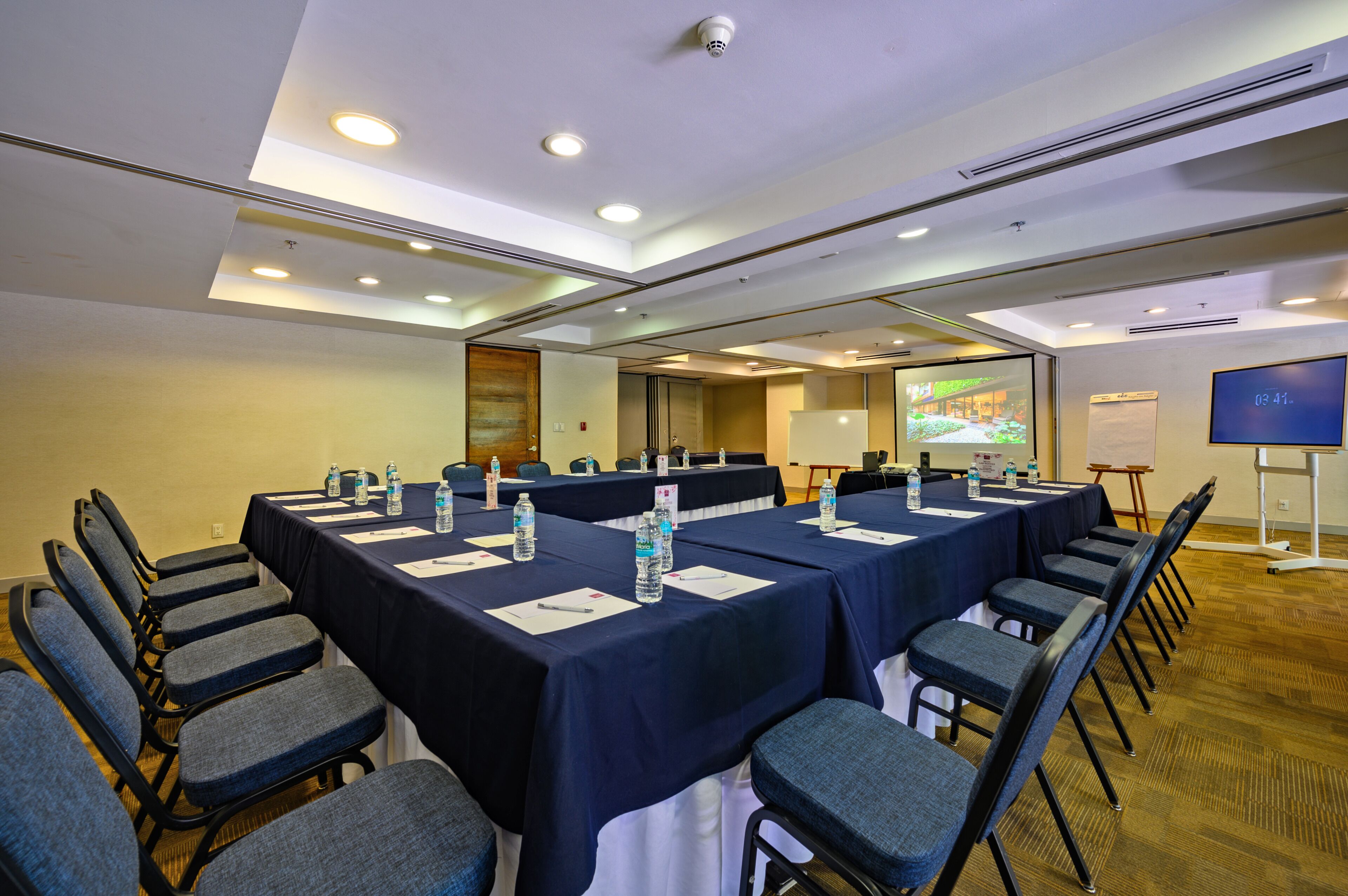A conference room with tables, chairs, and a projector screen.