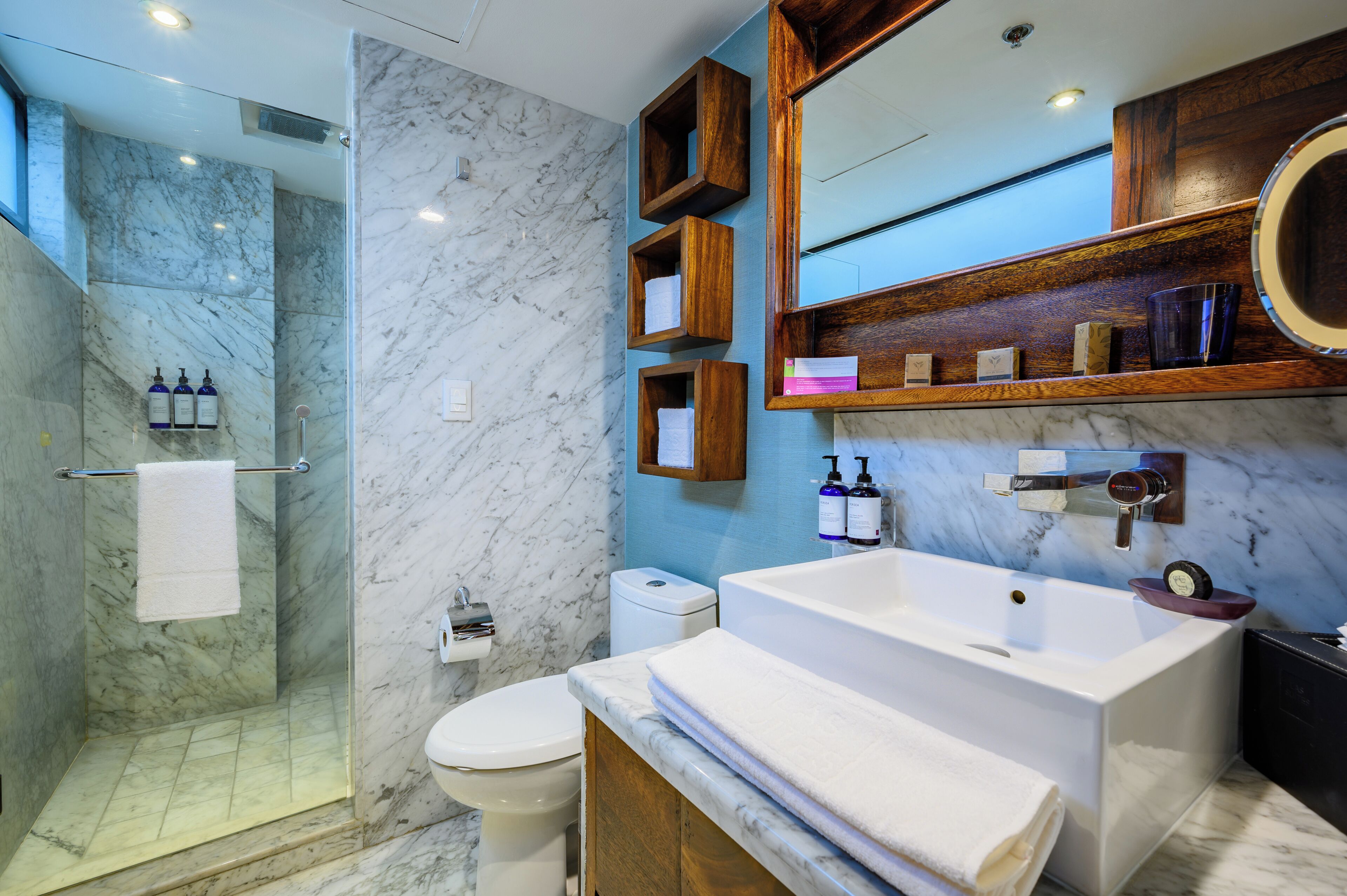 A modern bathroom with a glass-enclosed shower, a white sink, and a large mirror.