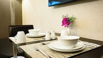 A dining table set with white plates, bowls, and cups, with a flower vase and salt shakers on the table.