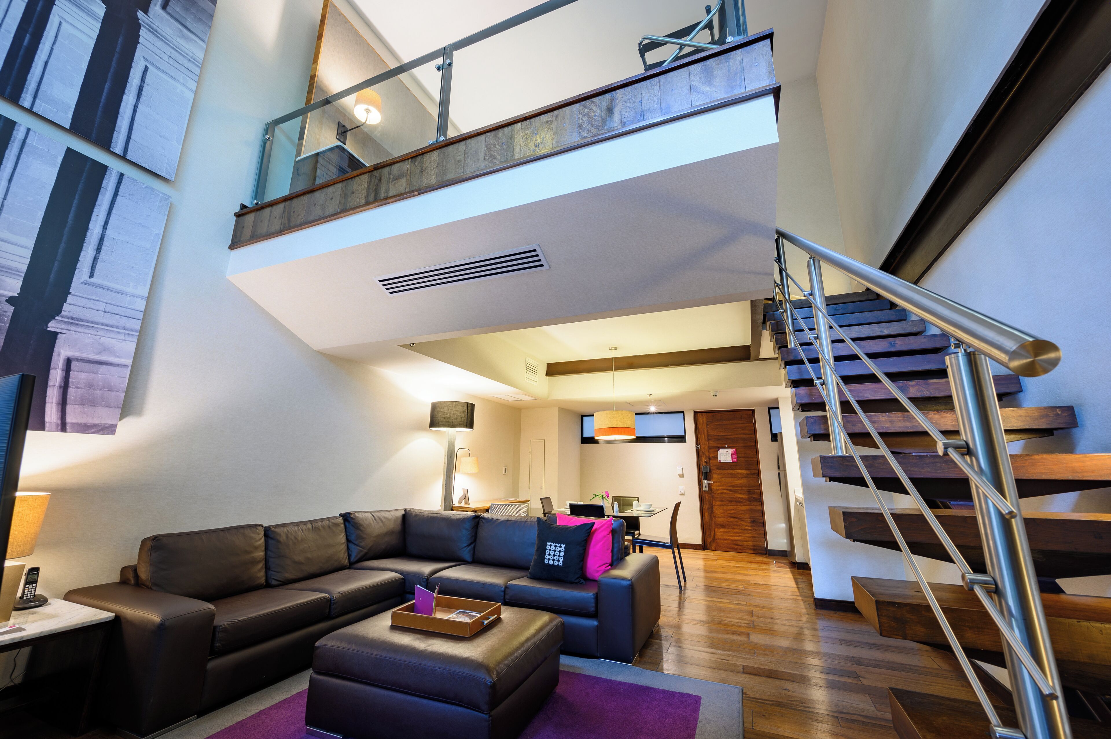 Una sala de estar moderna con un sofá modular, una mesa de centro y una escalera que conduce a un nivel superior.