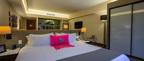 A hotel room with a large bed, bedside lamps, a flat-screen TV, a mirror, and a wardrobe.