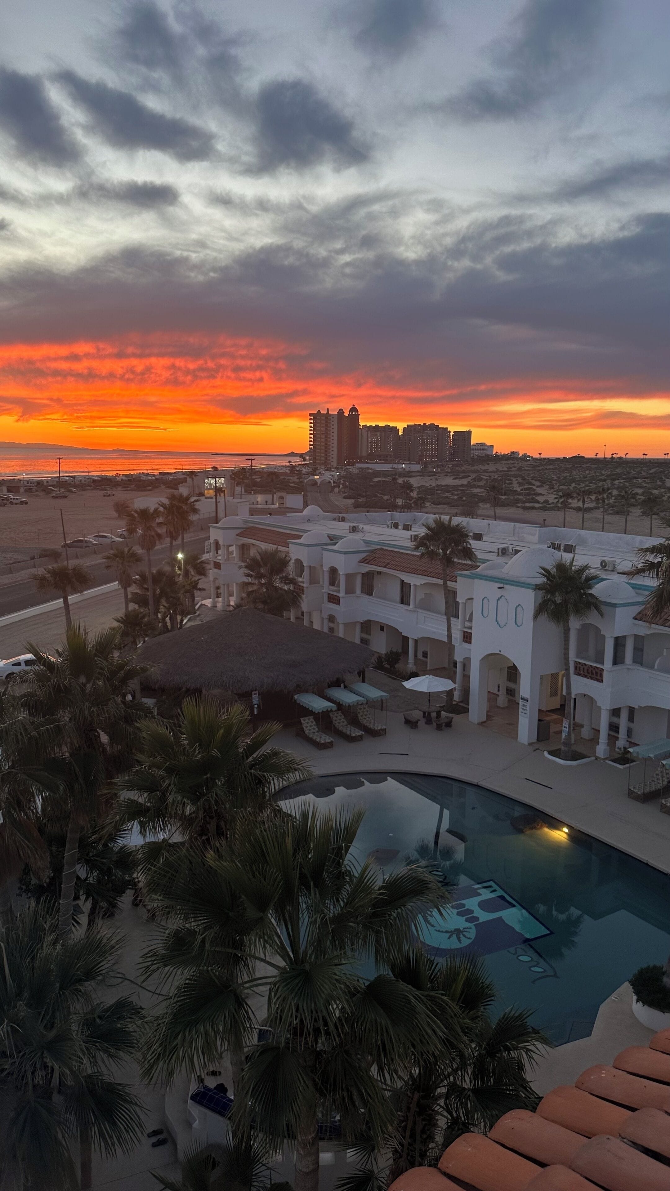 A resort with a pool, palm trees, and a sunset view.