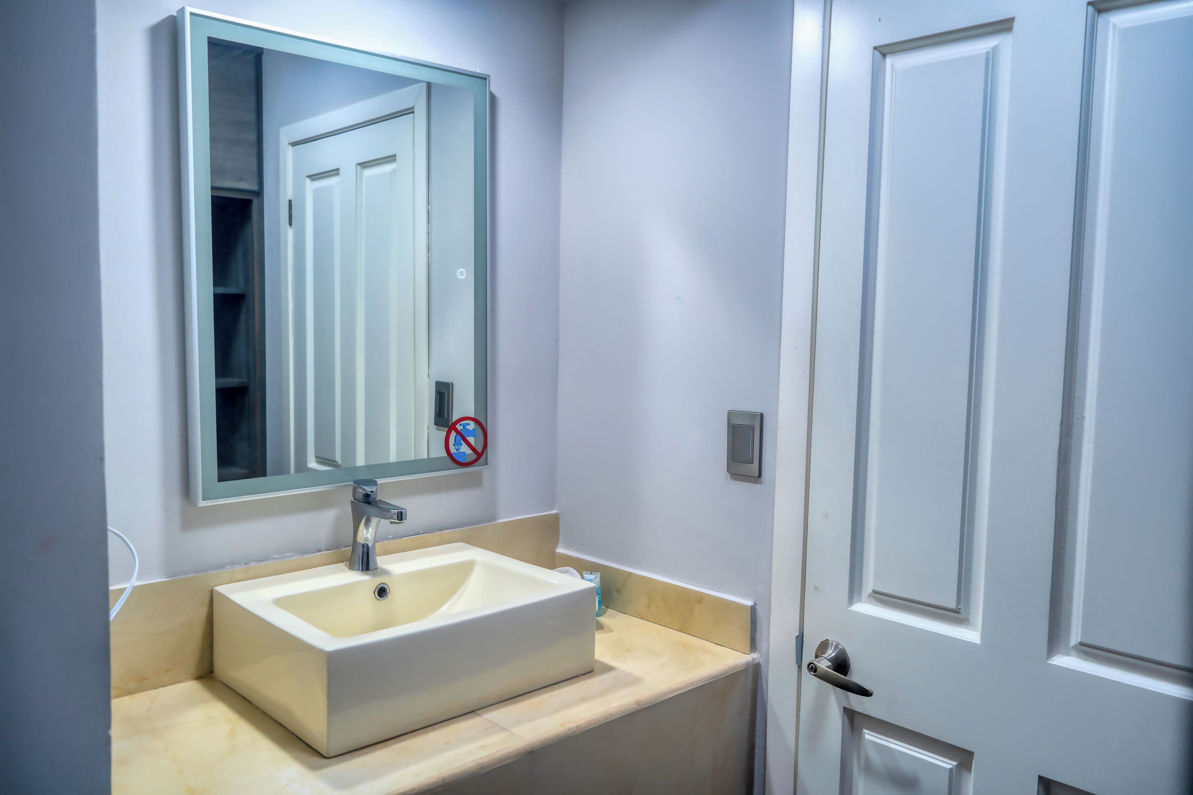 A bathroom with a white sink, a mirror, and a door.