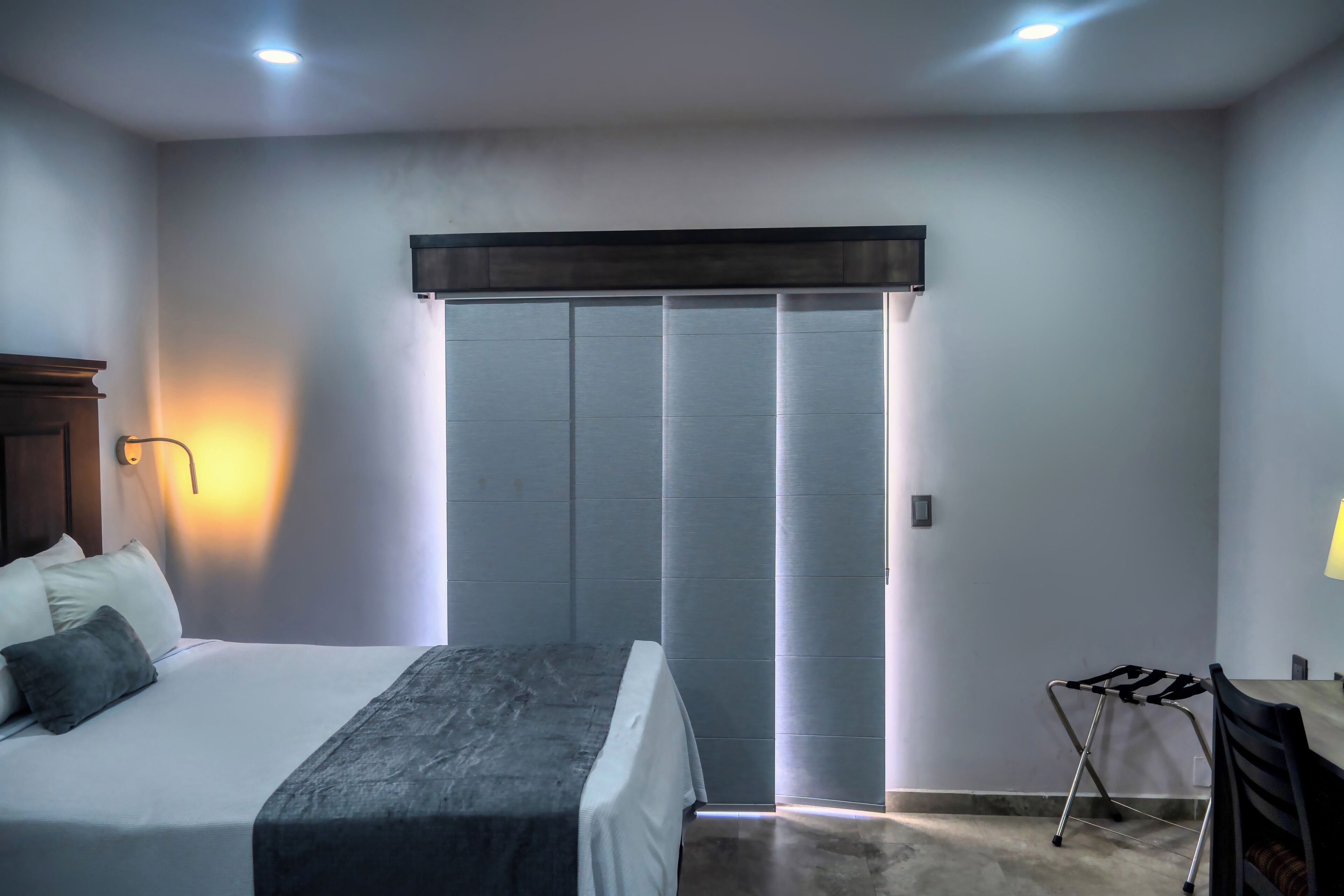 A bedroom with a bed, bedside table, lamp, and a sliding door closet.