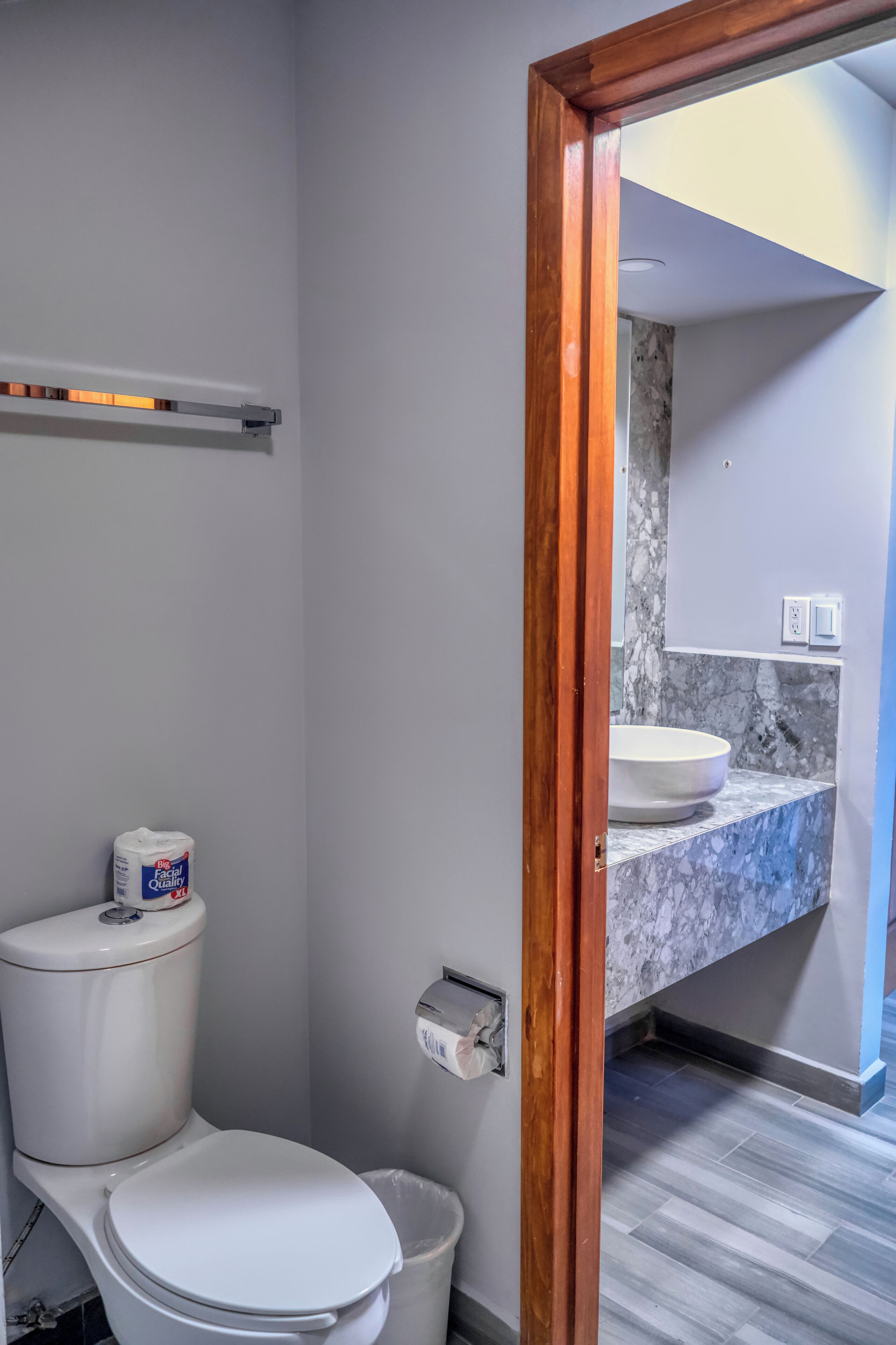 A bathroom with a toilet, a marble sink, and a wooden-framed doorway.
