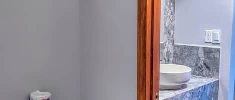 A bathroom with a toilet, a marble sink, and a wooden-framed doorway.