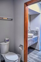 Un baño con inodoro, lavamanos de mármol y puerta con marco de madera.