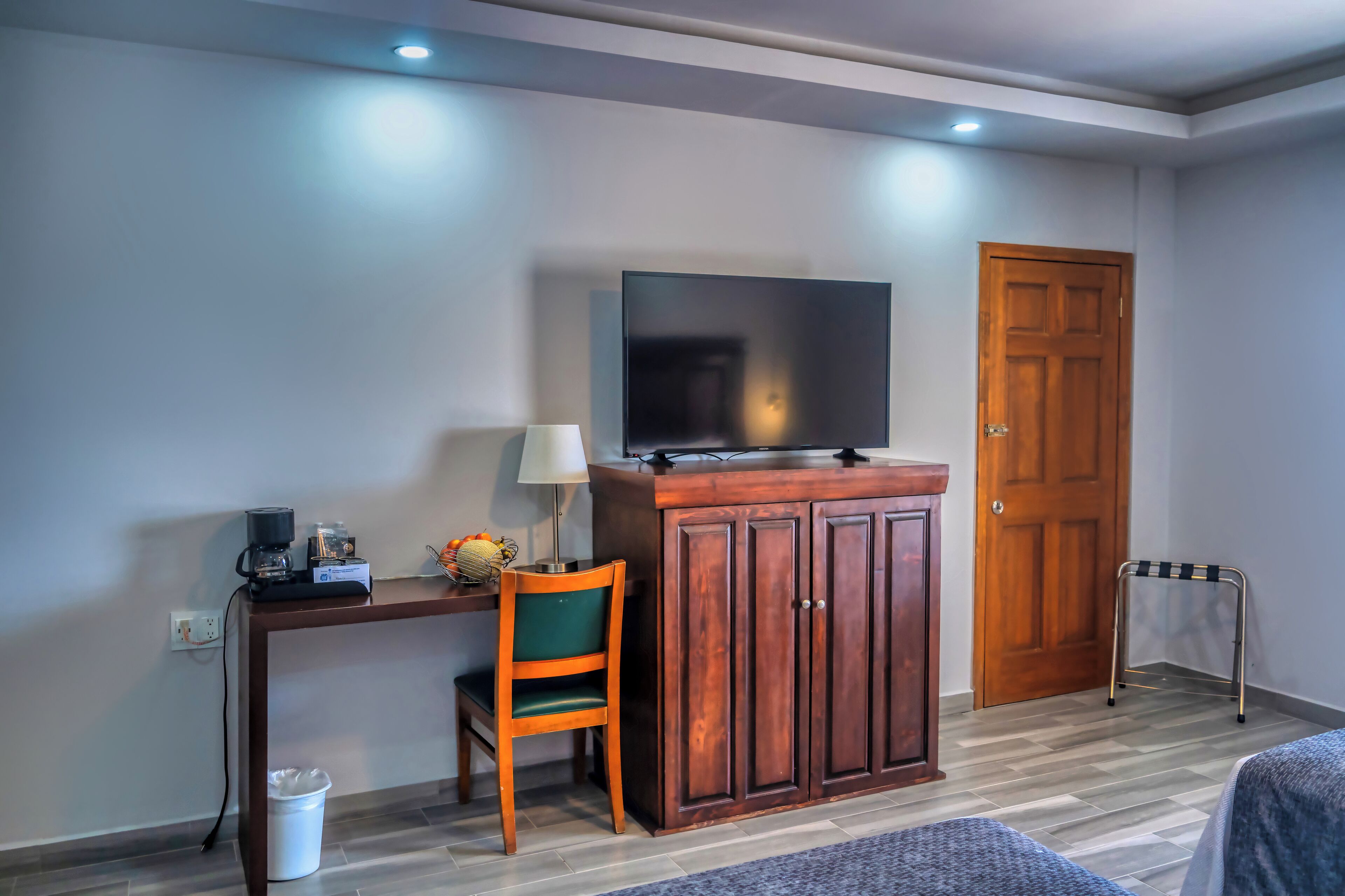 A room with a wooden desk, a television, a chair, a cabinet, and a door.