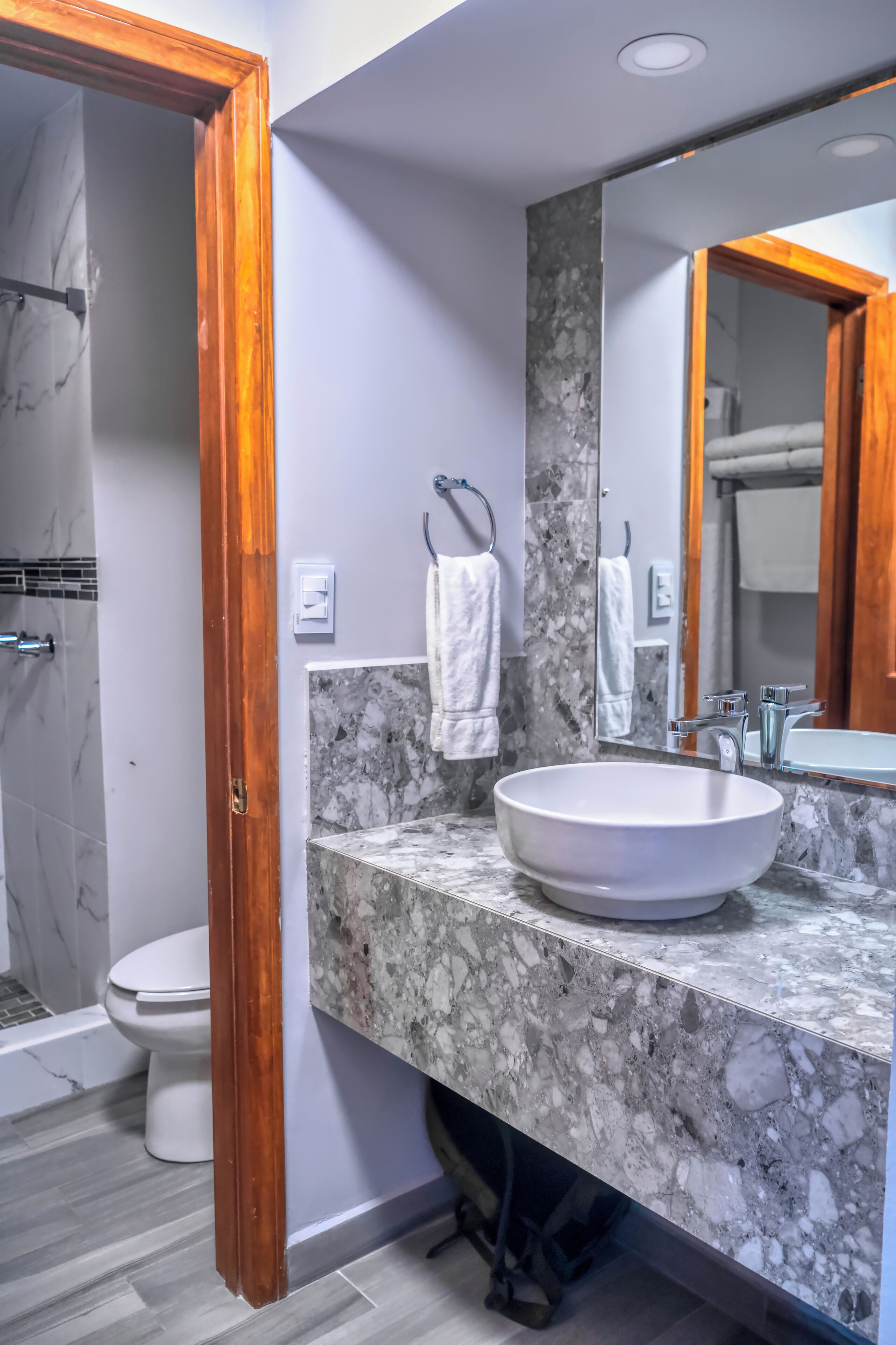 Un baño con lavamanos de mármol, un espejo grande y una ducha.