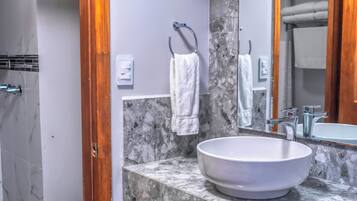 Un baño con lavamanos de mármol, un espejo grande y una ducha.