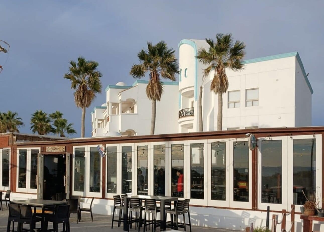 A coastal building with large windows and outdoor seating.
