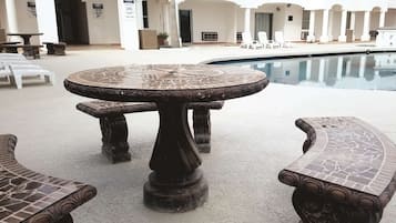 A poolside area with a mosaic-tiled table and benches.