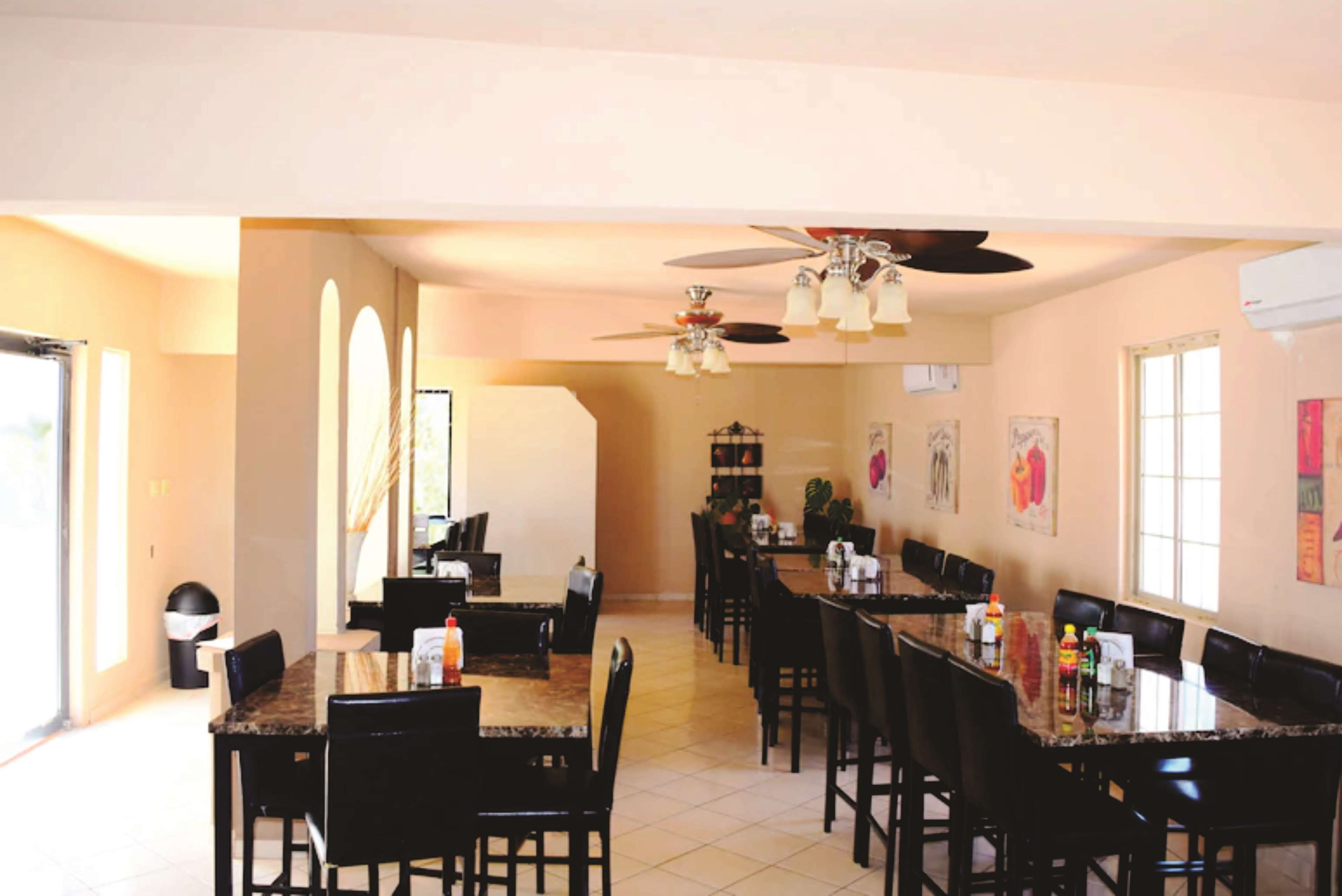 A spacious dining area with a high ceiling fan, multiple dining tables, and chairs.