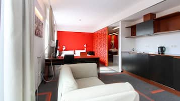 Una habitación de hotel moderna con kitchenette, un sofá y una pared de acento roja.