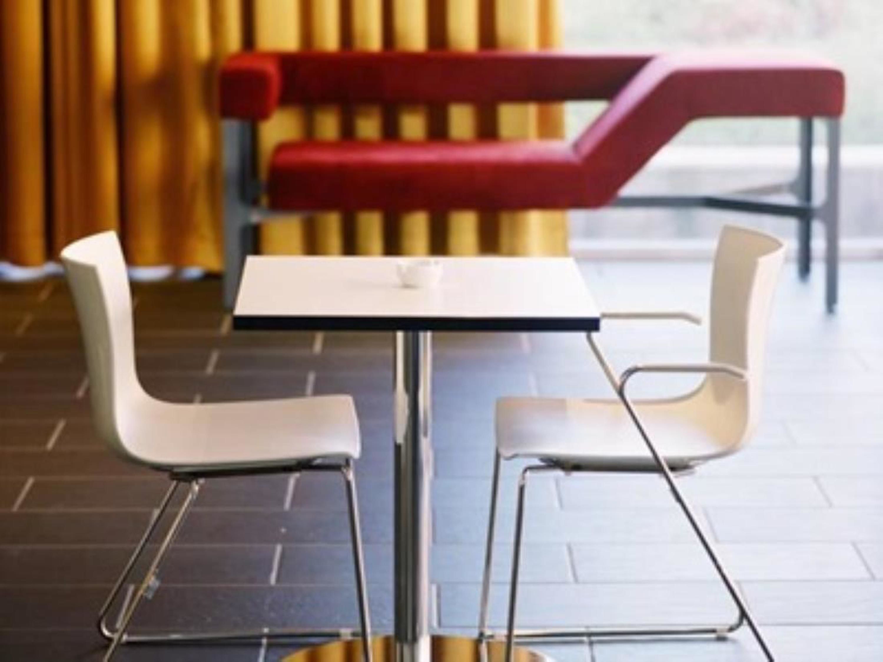 A modern dining area with a white table and four white chairs.